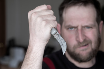 an angry man with a curved knife in his hand