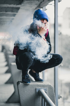 man surrounded in smoke and looking out a window