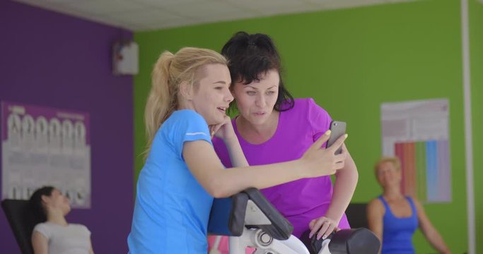Young woman shows photos on smartphone to her personal instructor