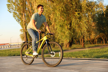 Fototapeta na wymiar Handsome young man riding bicycle on city waterfront