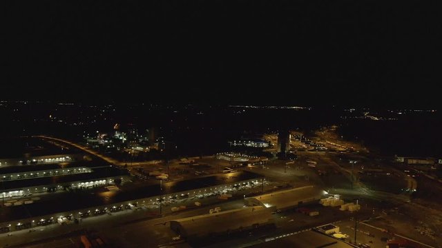 Docks at dark night. Drone flying over warehouse and containers on the harbor. Cargo and shipping industry.