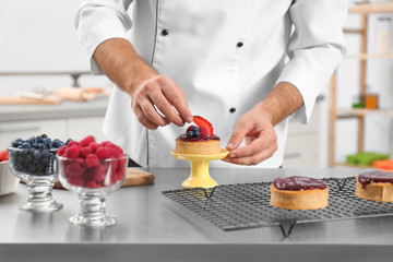 Male pastry chef preparing dessert at table in kitchen, closeup