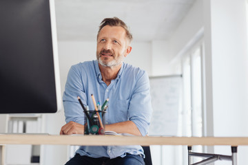 Businessman sitting working at a large monitor - obrazy, fototapety, plakaty