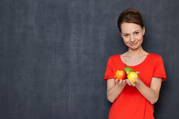 Portrait of happy woman holding nectarines and apple in hands