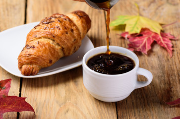Autumn breakfast with french croissant and a cup of coffee.