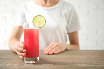 Young woman with glass of tasty refreshing drink at wooden table, closeup