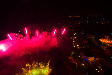 Fototapeta na wymiar A bright pink flash of fireworks over a city at night. Shooting with the drone. Selective focus. Motion blur. Copy space
