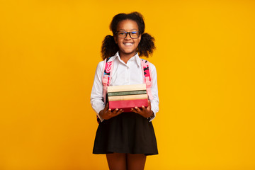 African American First-Grade Schoolgirl Holding Books In Studio