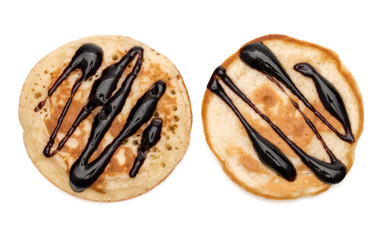 Two pancakes with chocolate syrup isolated on white background cutout. Top view.