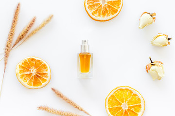 Composition with perfume and dry oranges on white background top view