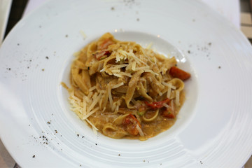 Italian pasta with pistachio cream and grand padana cheese and cherry tomatoes in restaurant. Tasty food.