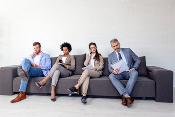 Group of four business people sitting on sofa