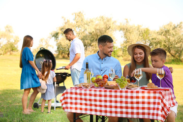 Happy families with little children having picnic in park
