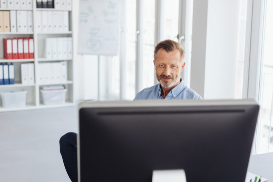 Businessman working behind a large desktop monitor