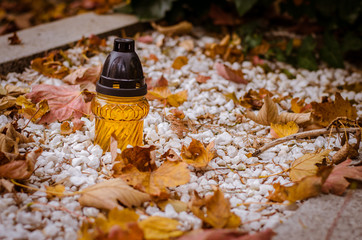 candle and autumnal leaves during All Saints Day in the cemetery