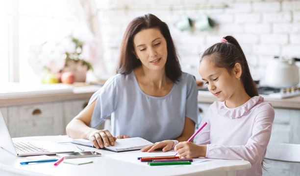 Beautiful mother helping her daughter with homework