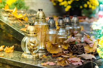 burning candles and autumnal colorful leaves on the grave