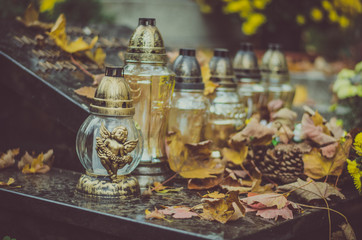 burning candles and autumnal colorful leaves on the grave