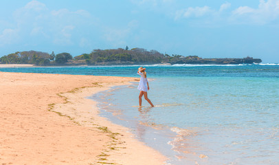 Young woman walking along the beach. side view - Side view of blond woman in fashionable style summer outfit