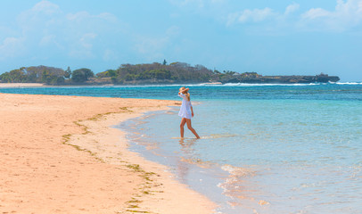 Obraz premium Young woman walking along the beach. side view - Side view of blond woman in fashionable style summer outfit