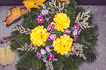 autumnal floral decoration on grave during All Saints Day in the cemetery