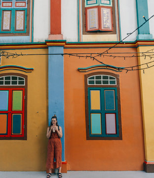 Woman standing against colorful building, Singapore