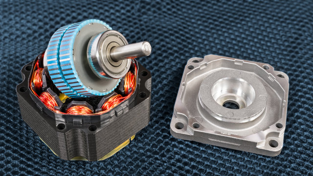 Disassembled electric step motor parts on a dark grid background. Blue rotor with steel shaft on black stator with electromagnetic coils and copper wire winding. Aluminum cast of ball bearing housing.