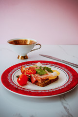 slice of bread with smoked ham, cheese and tomatoes on red plate