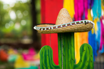 Cactus in sombrero hat over party ribbons background outdoor