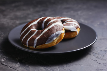 Glazed chocolate donut on black plate
