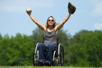 Woman in wheelchair playing catch in a green field