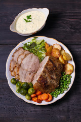 Roasted sliced ham, vegetables and sauce. View from above, top studio shot