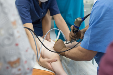 A team of urologist doctors performing a cystoscopy using a cystoscope. In a sterile operating room. close-up