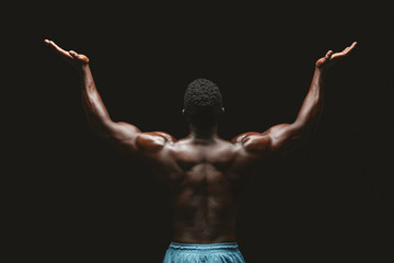 Back view of black bodybuilder raising his hands up