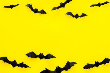 Bats cutout on Halloween frame on yellow table top view copy space