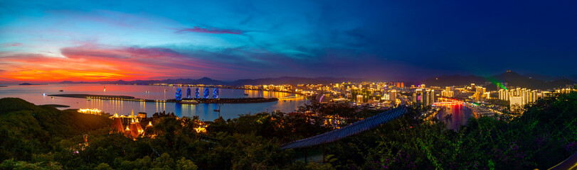 Night view of Phoenix island and Sanya city illuminated with city lights. View from Luhuitou Park on Hainan Island, China