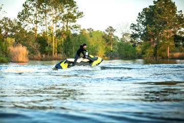 Teenage boy man driving a personal watercraft outside on a lake pond at sunset