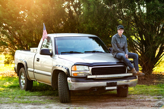 teenage boy from the south standing in front of his pickup truck  serious and thoughtful