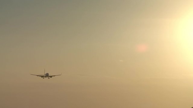 Small jet airplane is landing in windy weather during beautiful yellow sunset