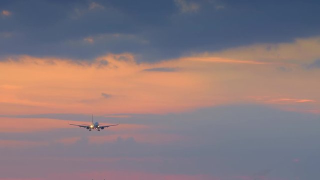 Silhouette of small jet airplane is landing in airport in yellow blue sunset with wind