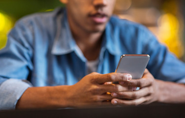 Cropped photo of black guy in causal clothes using cellphone