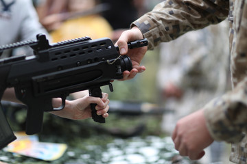 A man in camouflage uniforms explains the design of an automatic training weapon