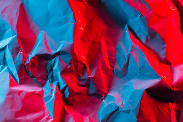 Crushed paper background in vibrant bold gradient holographic neon colors. Fire background imitation. Flat lay. Top view.