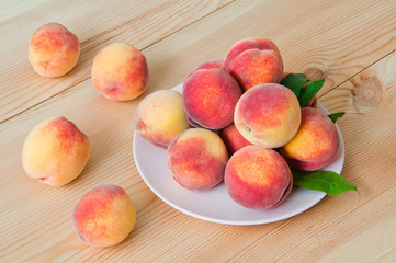 Fresh organic peaches in a plate on a wooden table