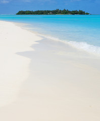 Fototapeta premium Beautiful white sand Maldivian beach and absolutely clear blue waters of Indian Ocean with a tropical paradise island on the background