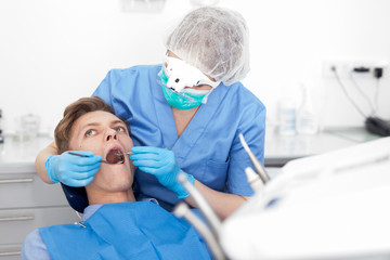 Dentist female in uniform is examinating of male in dental clinic