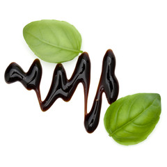 Balsamic vinegar cream and basil leaves isolated on white background. Italian salad dressing, sauce.