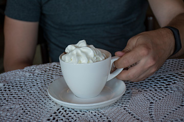 A guy with a cup of coffee in a cafe at the table, close-up.