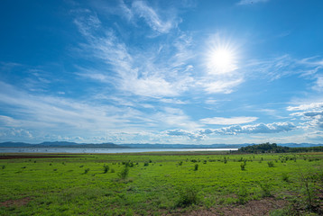 Fototapeta na wymiar large green field beside the dam in blue sky