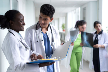 a group of mixed race doctors. Young people in white coats, standing in the hospital corridor, are...